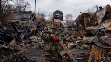 Yehor, 7, stands holding a wooden toy rifle next to destroyed Russian military vehicles near Chernihiv, Ukraine, Sunday, April 17, 2022. Witnesses said multiple explosions believed to be caused by missiles struck the western Ukrainian city of Lv...