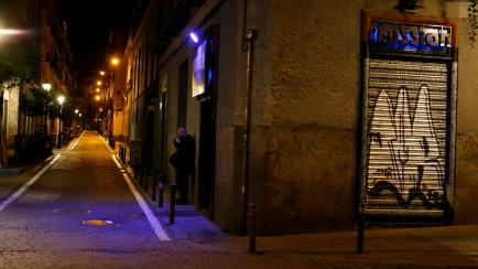 A man smokes along an empty street of shuttered shops, as Madrid's internationally famous night life shuts down due to the coronavirus pandemic, in central Madrid, Spain, March 13, 2020. REUTERS/Javier Barbancho