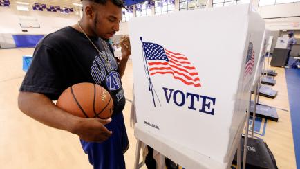 A resident holds his basketball while receiving assistance from an election official at a recreation center serving as polling place during the U.S. general election in Greenville, North Carolina, U.S. November 8, 2016.  REUTERS/Jonathan Drake