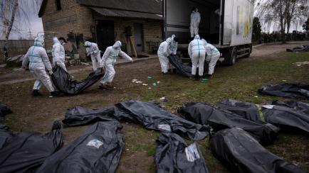 FILE - Volunteers load bodies of civilians killed in Bucha onto a truck to be taken to a morgue for investigation, in Bucha on the outskirts of Kyiv, Ukraine, Tuesday, April 12, 2022. (AP Photo/Rodrigo Abd, File)