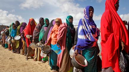 FILE - In this Saturday, May 18, 2019 file photo, newly-arrived women who fled drought line up to receive food distributed by local volunteers at a camp for displaced persons in the Daynile neighborhood on the outskirts of the Somalian capital M...
