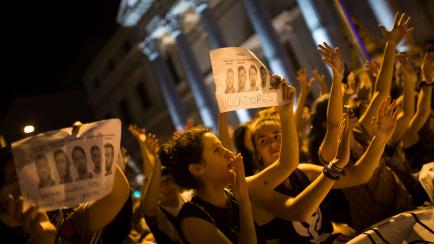 Women, some holding photographs of the five men known as "La Manada" or "The Pack" and reading: "Rapists", shout slogans outside the Spanish parliament during a protest in Madrid, Thursday, April 26, 2018. Women's rights groups are protesting af...