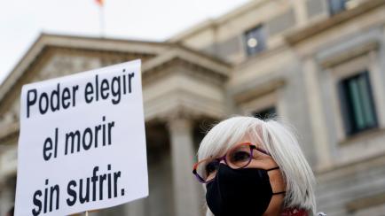 A person who is in favor of a law to legalise euthanasia, after Spanish Parliament voted in favor, holds a placard outside the Spanish Parliament in Madrid, Spain, December 17, 2020. The placard reads: "Being able to choose to die without suffer...