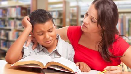 Upset Hispanic Young Boy and Famle Adult Studying At Library.