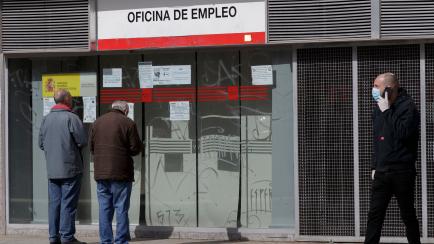 MADRID, SPAIN - MARCH 16: Two people read the posters of an employment office closed during the first working day since the state of alarm was decreed throughout the country as a result of the coronavirus on March 16, 2020 in Madrid, Spain. (Pho...