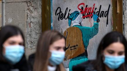 TOPSHOT - People walk past a new work by Italian street artist TvBoy depicting Santa Claus carrying the Covid-19 vaccine in his sack, in Barcelona on December 24, 2020. (Photo by Josep LAGO / AFP) / RESTRICTED TO EDITORIAL USE - MANDATORY MENTIO...