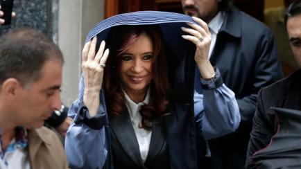 Argentina's former President Cristina Fernandez covers herself from the rain as she leaves her apartment for court in Buenos Aires, Argentina, Wednesday, April 13, 2016. Fernandez has been called to testify Wednesday in an alleged scheme to mani...