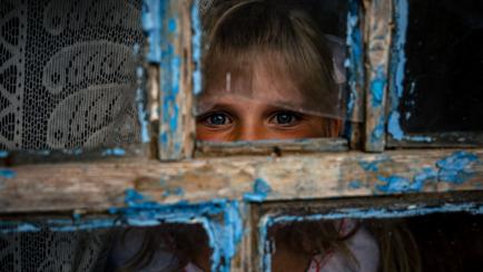 Antonina, de 9 años, mira a través de una ventana de su escuela, en el sur de Ucrania.