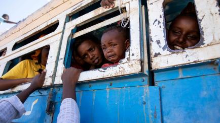 Refugees who fled the conflict in Ethiopia's Tigray region ride a bus going to the Village 8 temporary shelter, near the Sudan-Ethiopia border, in Hamdayet, eastern Sudan, Tuesday, Dec. 1, 2020. (AP Photo/Nariman El-Mofty)