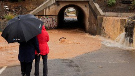 Two people watch rainwater caused by the tropical storm Hermine, in Vecindario, on the island of Gran Canaria, Spain, September 25, 2022. REUTERS/Borja Suarez
