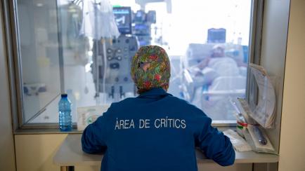 A healthcare worker watches a Covid-19 patient through the window, at the Intensive Care Unit (ICU) of the Bellvitge University Hospital in Barcelona on January 19, 2022. - Milder for most but still highly contagious, Omicron has filled intensiv...