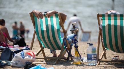 SOUTHEND-ON-SEA, ENGLAND  - JULY 25: Two people sit on the beach in deck chairs with a shisha pipe on July 25, 2019 in Southend-on-Sea, United Kingdom. The Met Office issued a weather warning from 3pm this afternoon. They warn that Britain could...