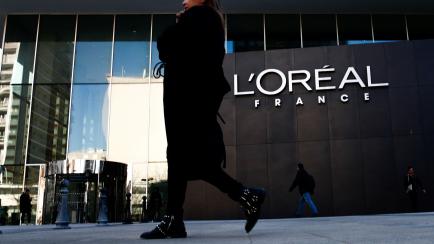 A woman walks by the logo of French cosmetics group L'Oreal in the western Paris suburb of Levallois-Perret, France, February 7, 2020. REUTERS/Gonzalo Fuentes