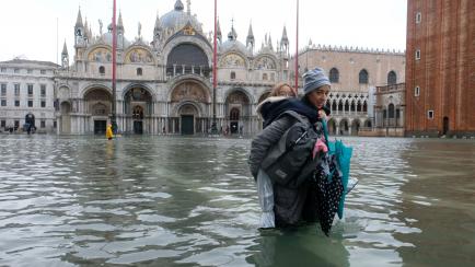 A woman with a child walks in the flooded St.Mark's Square during a period of seasonal high water in Venice, Italy November 12, 2019. REUTERS/Manuel Silvestri