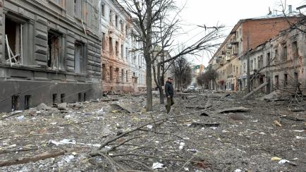 TOPSHOT - A pedestrian walks amid debris in a street following a shelling in Ukraine's second-biggest city of Kharkiv on March 7, 2022. - On the 12th day of Russia's invasion of Ukraine March 7, 2022, Russian forces pressed a siege of the key so...