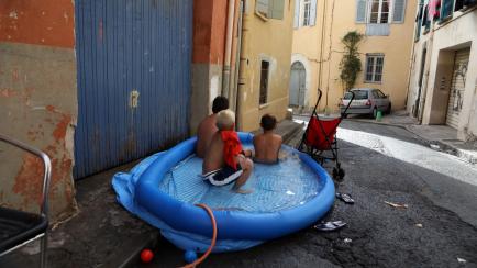 Children keep cool by sitting in a paddling pool in the Saint-Jacques neighbourhood of Perpignan, southern France on June 17, 2022. - French officials have urged caution as a record pre-summer heatwave spread across the country from Spain, where...