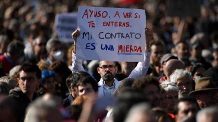 Un profesional sanitario porta una pancarta con el lema: "Ayuso, a ver si te enteras, mi contrato es una mierda"; en la manifestación por la sanidad pública en Madrid.