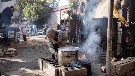 ANTONIVKA, UKRAINE - NOVEMBER 14: Civilians cook food outside on a fire on November 14, 2022 in Antonivka, Ukraine. As the first wave of joy from the liberation by the Ukrainian army subsides, residents are beginning to think about life in the f...