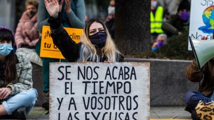 MADRID, SPAIN - 2021/03/19: A climate change activist of 'Fridays for Future' group with a placard reading 'We are running out of time and you are running out of excuses' protesting in front of the Spanish Parliament calling for action in climat...