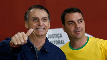 Presidential frontrunner Jair Bolsonaro, of the Social Liberal Party, left, accompanied by his son Flavio Bolsonaro, flashes a thumbs up as he arrives to vote in the general election, in Rio de Janeiro, Brazil, Sunday, Oct. 7, 2018. Brazilians c...