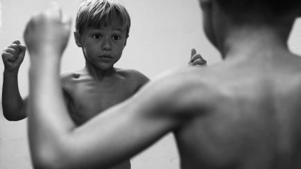 6 yr old boy flexing muscles in the mirror
