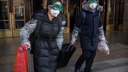 BEIJING, CHINA - JANUARY 31: A Chinese couple wear protective masks and goggles after getting off a train as they and others return after the Spring Festival holiday on January 31, 2020 in Beijing, China. The number of cases of a deadly new coro...