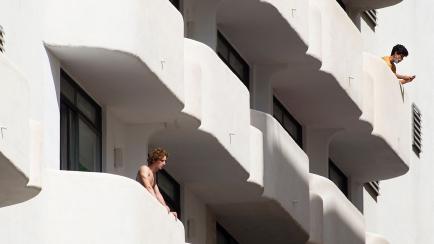Young men stand on balconies of an hotel where students who had contact with COVID-19 patients are quarantined in Palma de Mallorca on June 29, 2021. - An end-of-year student trip to Spain's Balearic Islands has sparked a major coronavirus clust...