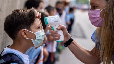 Una maestra con mascarilla para protegerse contra la propagación del coronavirus revisa la temperatura de un alumno en la escuela Maestro Padilla, al inicio del año escolar, el martes 7 de septiembre de 2021, en Madrid, España. (AP Foto/Manu ...