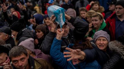 FILE - Residents gathering at an aid distribution point receive supplies in downtown Kherson, southern Ukraine, Friday, Nov. 18, 2022. Ukraine liberated Kherson more than one week ago, and the cityâs streets are revived for the first time i...