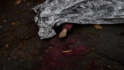 The body of a woman killed during a Russian attack is covered with an emergency blanket before being transported to the morgue in Kherson, southern Ukraine, Friday, Nov. 25, 2022. A barrage of missiles struck the recently liberated city of Khers...