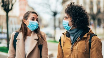 Young couple meet in quarantine outside on the city street wearing face protective mask to prevent Coronavirus and anti-smog