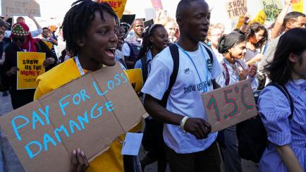 FILE - Vanessa Nakate, of Uganda, left, participates in a Fridays for Future protest at the COP27 U.N. Climate Summit while holding a sign that says "pay for loss and damage", Friday, Nov. 11, 2022, in Sharm el-Sheikh, Egypt. (AP Photo/Peter Dej...