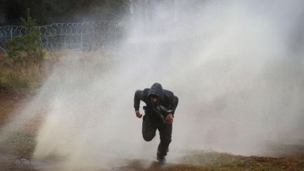 Un hombre huye de un cañón de agua durante los enfrentamientos entre los migrantes y la policía polaca.