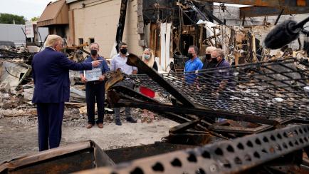 President Donald Trump talks to business owners Tuesday, Sept. 1, 2020, as he tours an area damaged during demonstrations after a police officer shot Jacob Blake in Kenosha, Wis. (AP Photo/Evan Vucci)
