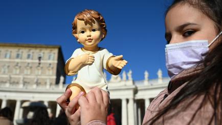 Una niña sostiene una imagen de Jesús la tradicional bendición papal de figurita, en la Plaza de San Pedro de Roma. 