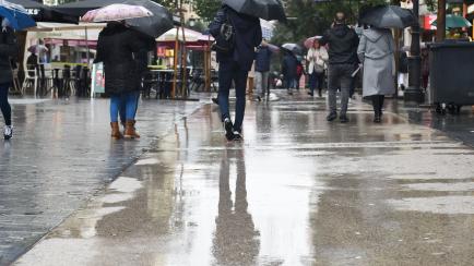 La gente camina por la calle con paraguas, en Madrid. 