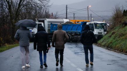 People walk near the barricade in the northern part of the ethnically-divided town of Mitrovica, Kosovo, December 11, 2022. REUTERS/Florion Goga