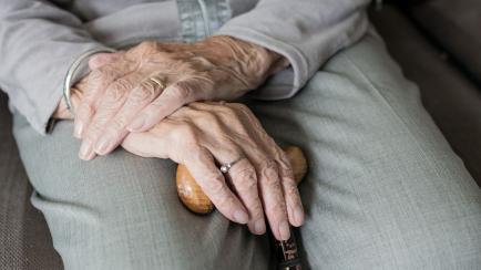 Una persona de avanzada edad sostiene un bastón