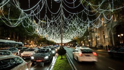 Tráfico en una calle de Madrid, iluminada por las luces de Navidad