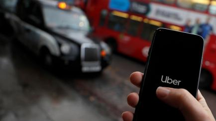 In this posed picture, the Uber app is opened on a mobile phone, backdropped by other transport services in London, Monday, Nov. 25, 2019.  London’s transit authority on Monday refused to renew Uber’s license to operate, with the ride-hailin...