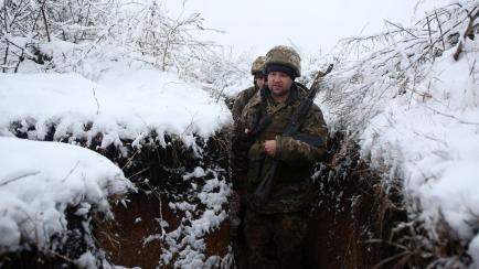 Ukrainian servicemen walk in a trench on their position on the front line with Russia-backed separatists near the small town of Svitlodarsk, in Donetsk region, on December 18, 2021. (Photo by Anatolii STEPANOV / AFP) (Photo by ANATOLII STEPANOV/...