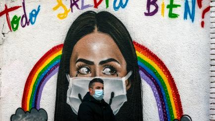A man wearing a face mask walks past a graffiti reading in Spanish "Everything will be alright?" in Barcelona, Spain, Tuesday, Jan. 26, 2021. With nearly 2.5 million infections and 55,400 deaths for COVID-19 since the beginning of the pandemic, ...