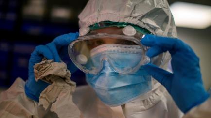 A health worker adjusts her googles as she takes a sample for a PCR test for the COVID-19 at a local hospital in Hospitalet, in Barcelona province, Spain, Tuesday, July 14, 2020. Outbreaks in northern Spain and in the city of Barcelona are not o...