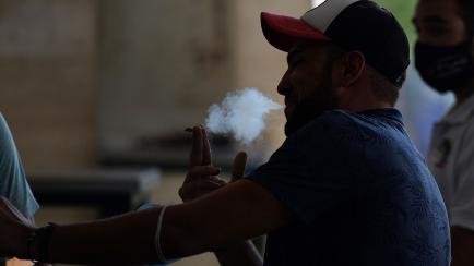 A man smokes at the terrace of a bar in Sevilla on August 13, 2020. - Spanish regions Galicia and Canary Islands attracting tourists introduced outdoor smoking bans to curb the coronavirus as a top domestic medical body called for a more coordin...