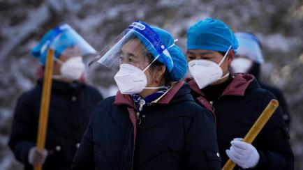 Workers wearing face shields and masks to help protect from the coronavirus prepare to clear the snow outside a health quarantine hotel Saturday, March 19, 2022, in the Yanqing district of Beijing, as the capital city was hit by a snowstorm. (AP...