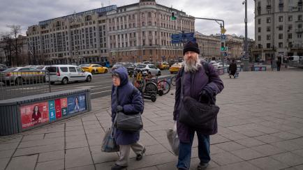 An elderly couple walks in a main street in Moscow, Russia, Monday, March 14, 2022. (AP Photo)