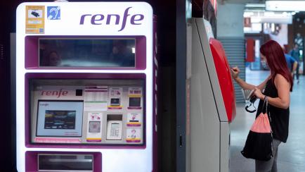 Una persona compra un billete en una taquilla de venta automática de Renfe