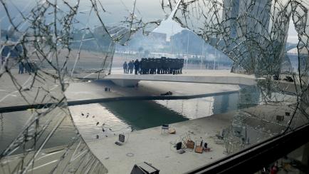 La Policía Militar vista a través de un cristal roto en la explanada junto al Congreso de Brasil.