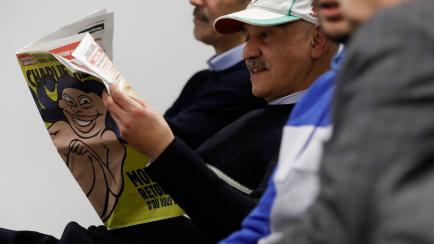 Brussels (Belgium), 10/01/2023.- Iranian opposition member smiles reading Charlie Hebdo with the front page anti Mollah on the side of the presentation of book 'Iran Democratic Revolution,' written by politicians and experts on Iran, during a pr...