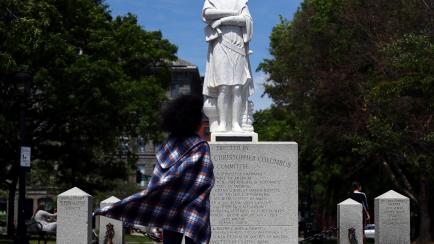 BOSTON, MASSACHUSETTS - JUNE 10: A woman looks at a statue depicting Christopher Columbus with its head removed at Christopher Columbus Waterfront Park on June 10, 2020 in Boston, Massachusetts. The statue was beheaded overnight and is scheduled...